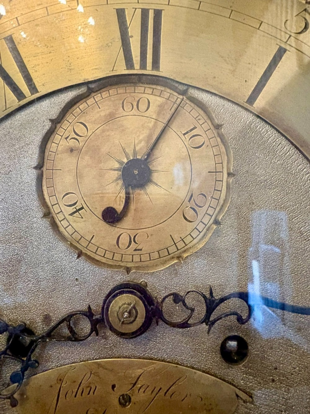 An antique Georgian longcase grandfather clock crafted from flame mahogany wood with an arched brass dial and brass finials. View XII