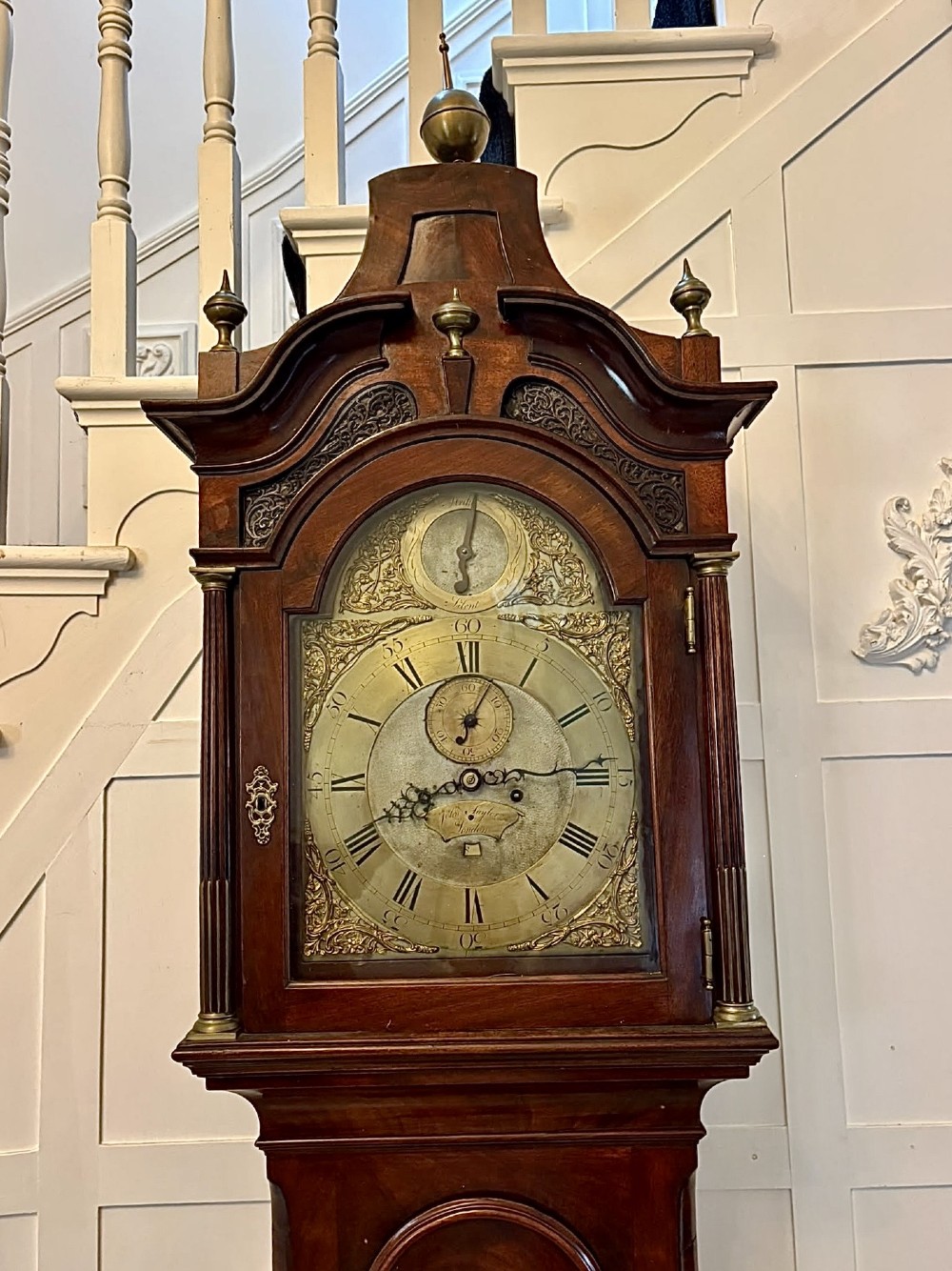 An antique Georgian longcase grandfather clock crafted from flame mahogany wood with an arched brass dial and brass finials. View XIV