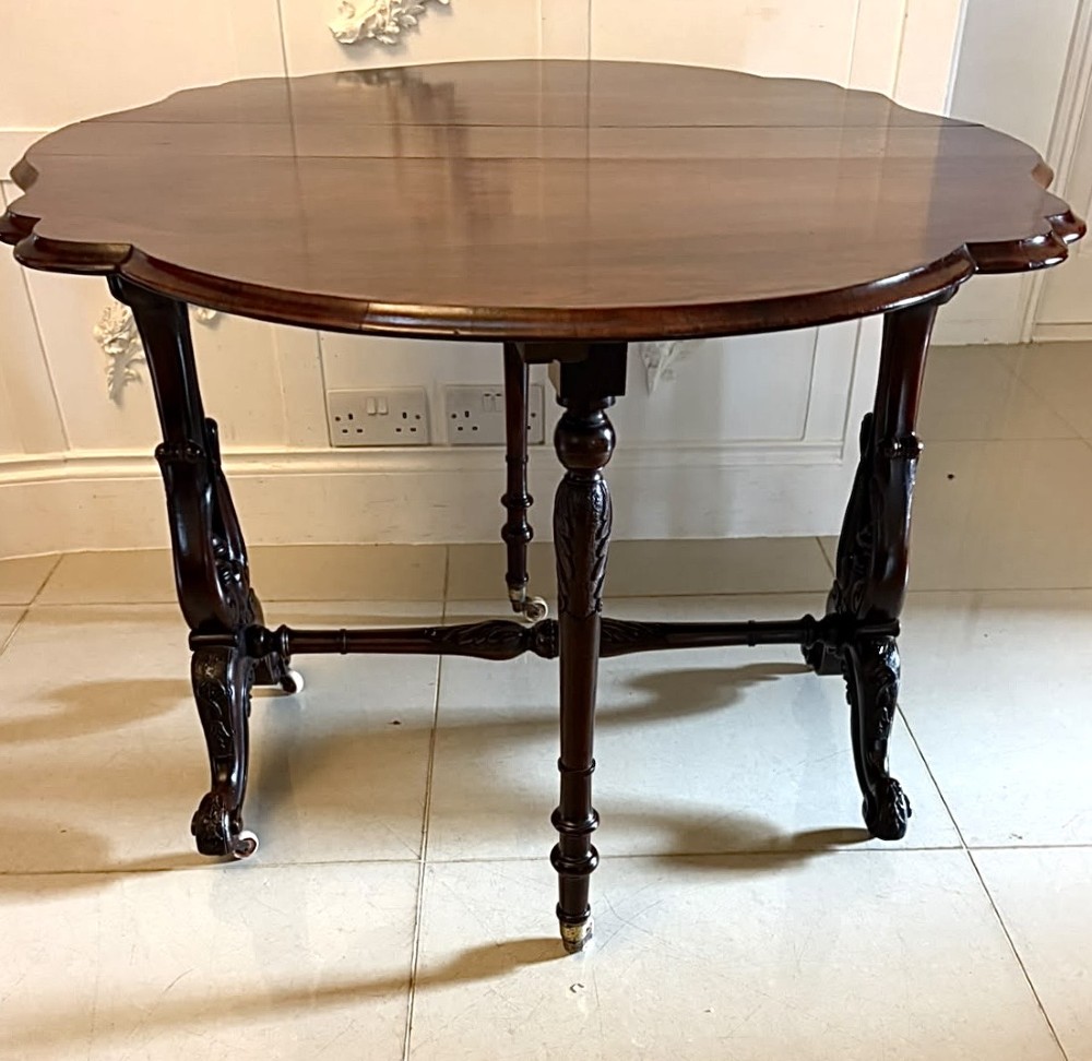 An antique Victorian rosewood Sutherland table with drop leaves, carved legs, and brass castors. View IV