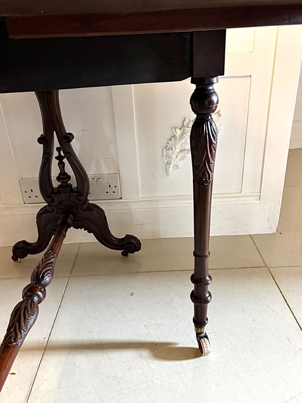 An antique Victorian rosewood Sutherland table with drop leaves, carved legs, and brass castors. View VI