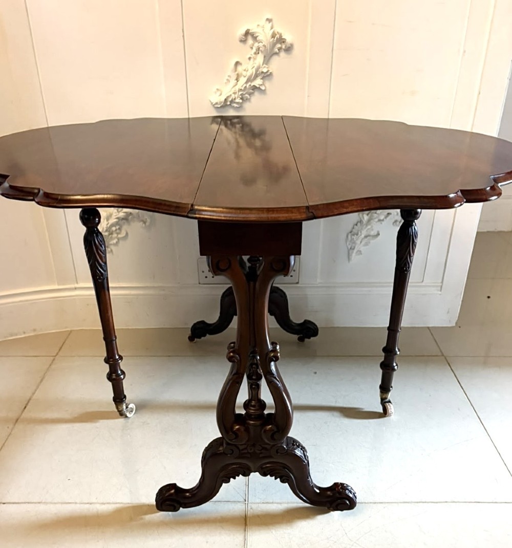 An antique Victorian rosewood Sutherland table with drop leaves, carved legs, and brass castors. View VII