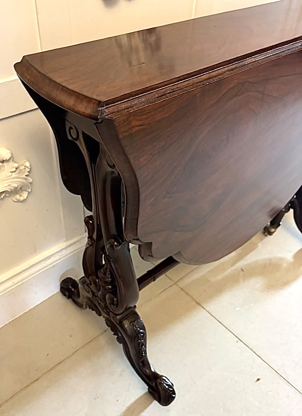 An antique Victorian rosewood Sutherland table with drop leaves, carved legs, and brass castors. View X