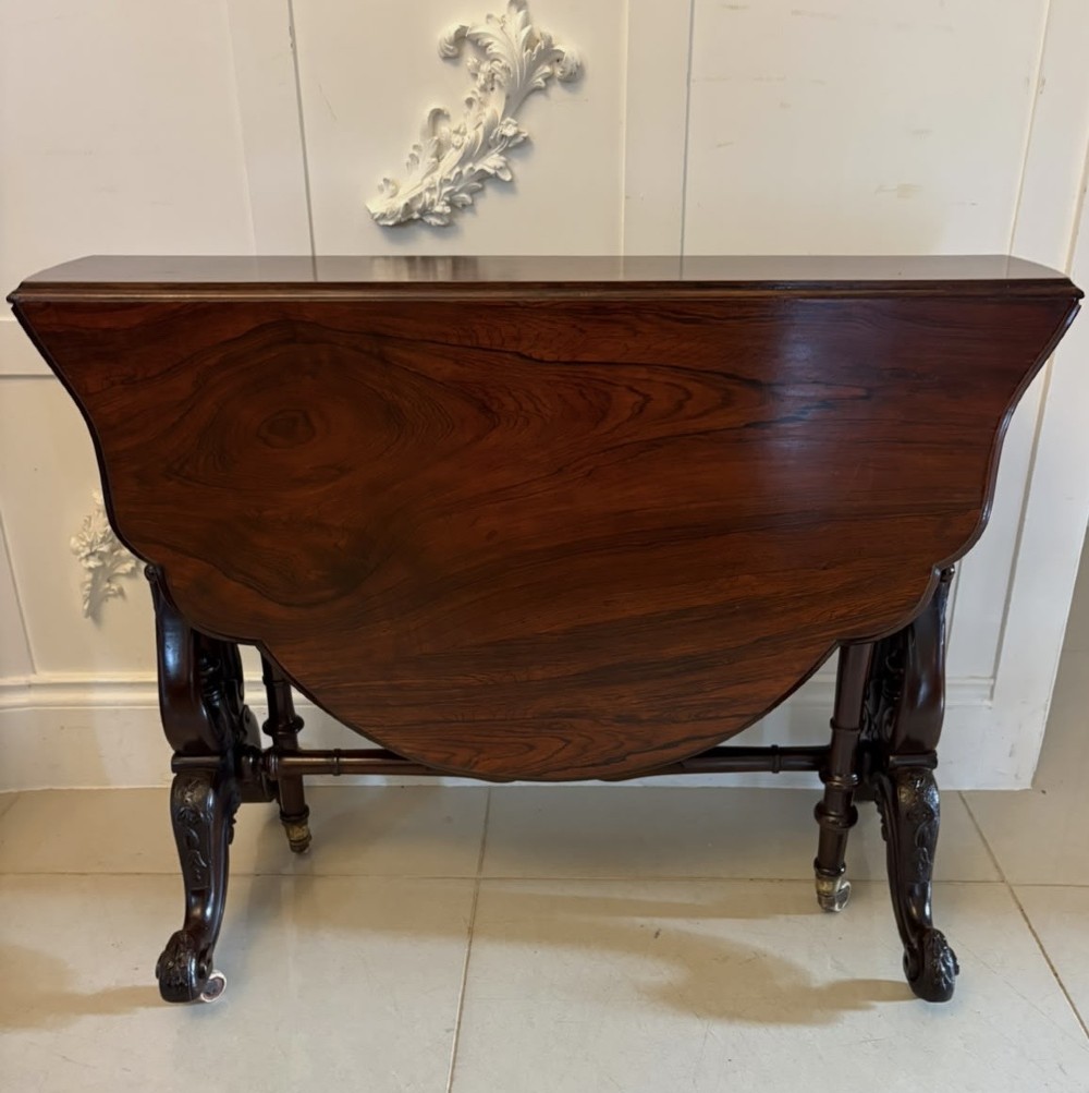An antique Victorian rosewood Sutherland table with drop leaves, carved legs, and brass castors. View XV