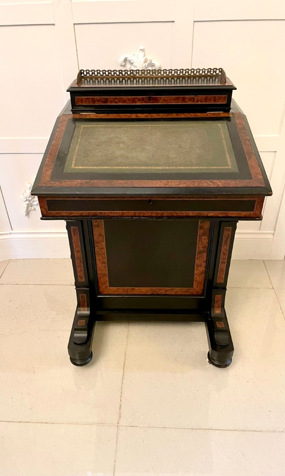 A Victorian ebonised davenport desk featuring walnut crossbanding, a sloped green leather writing surface, side drawers, and a top brass gallery rail. View VIII