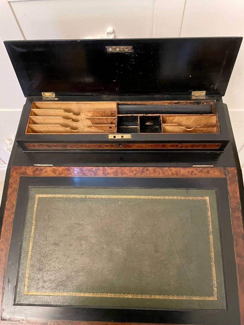 A Victorian ebonised davenport desk featuring walnut crossbanding, a sloped green leather writing surface, side drawers, and a top brass gallery rail. View IX