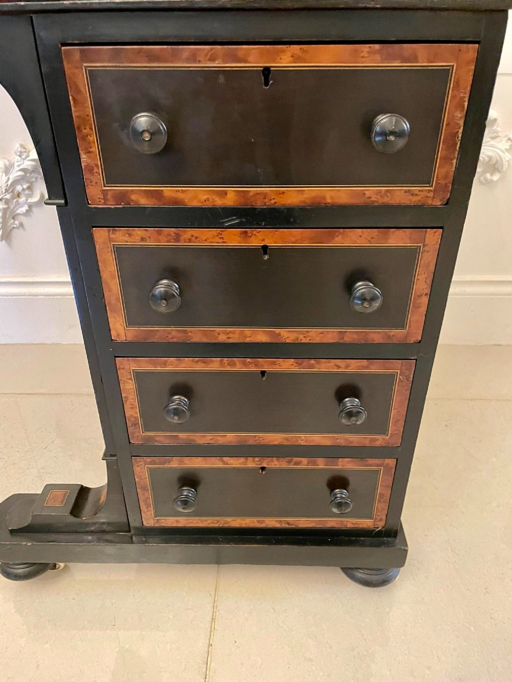 A Victorian ebonised davenport desk featuring walnut crossbanding, a sloped green leather writing surface, side drawers, and a top brass gallery rail. View X