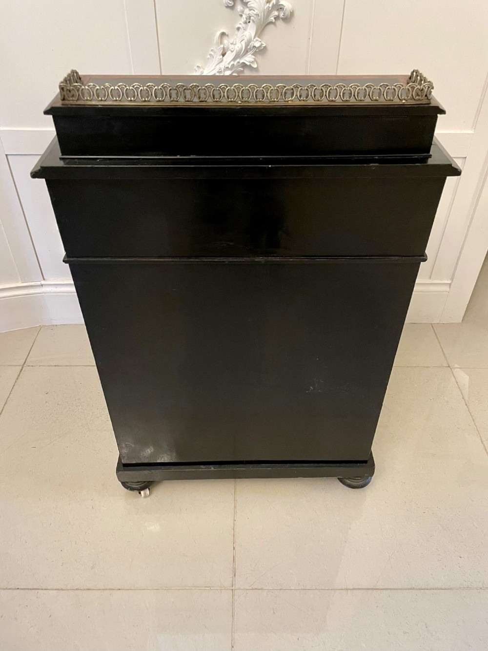 A Victorian ebonised davenport desk featuring walnut crossbanding, a sloped green leather writing surface, side drawers, and a top brass gallery rail. View XI