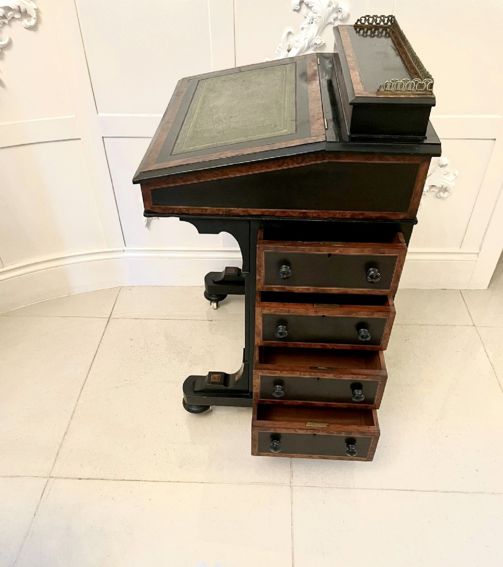 A Victorian ebonised davenport desk featuring walnut crossbanding, a sloped green leather writing surface, side drawers, and a top brass gallery rail. View XII