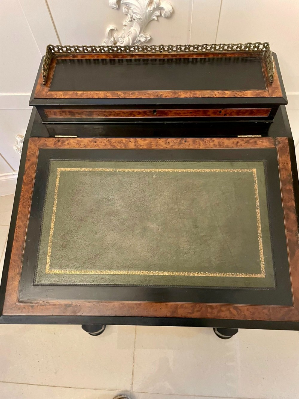 A Victorian ebonised davenport desk featuring walnut crossbanding, a sloped green leather writing surface, side drawers, and a top brass gallery rail. View XIII
