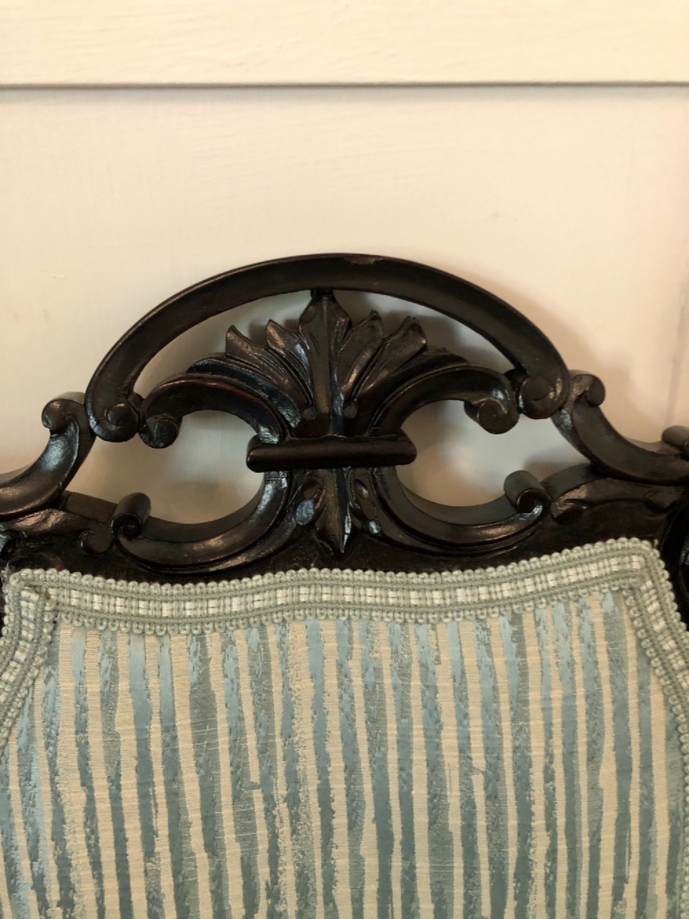 A pair of Victorian black lacquered armchairs featuring carved openwork backrests, padded armrests, and pale green striped upholstery. View IX