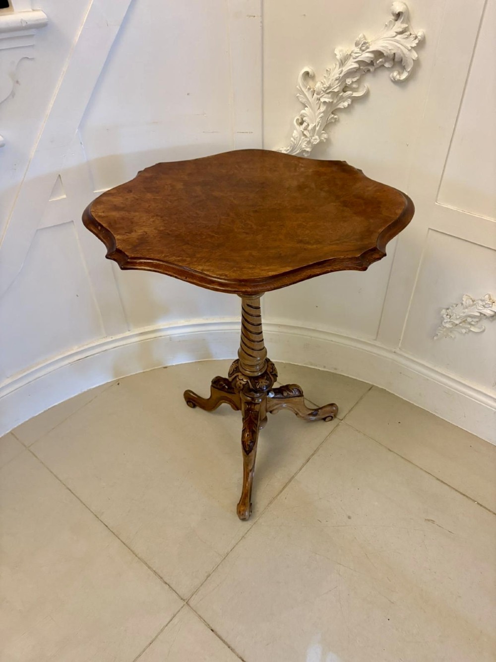 An antique Victorian burr walnut side table featuring a shaped scalloped top, a spiral carved pedestal column, and three carved cabriole legs.