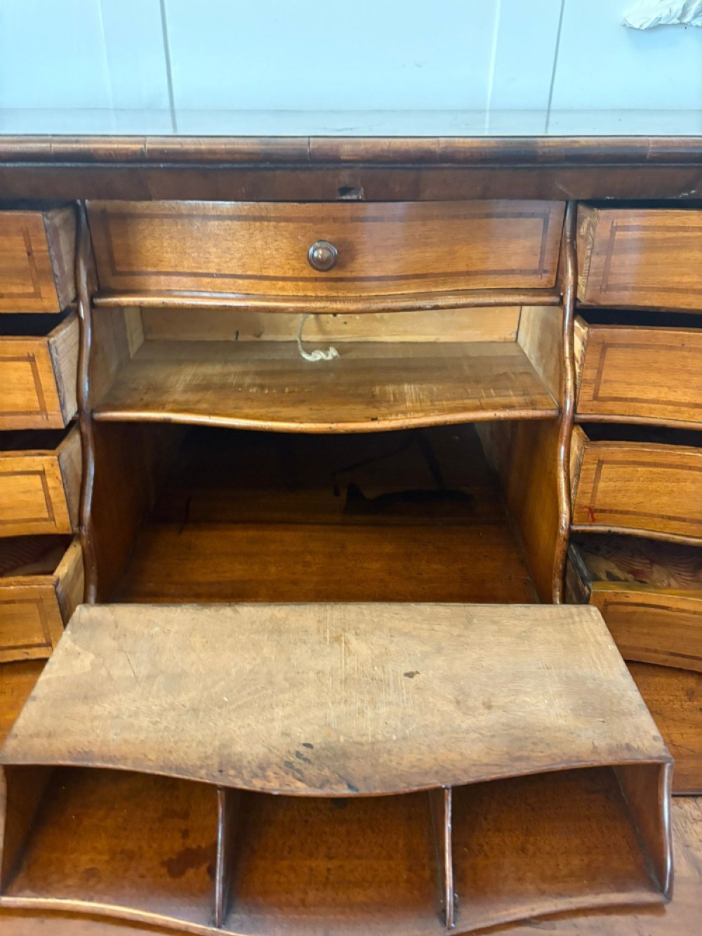 An 18th-century French walnut bureau featuring geometric parquetry inlay, a sloped fall front, a bombee body with two drawers, and brass mounts. View VIII