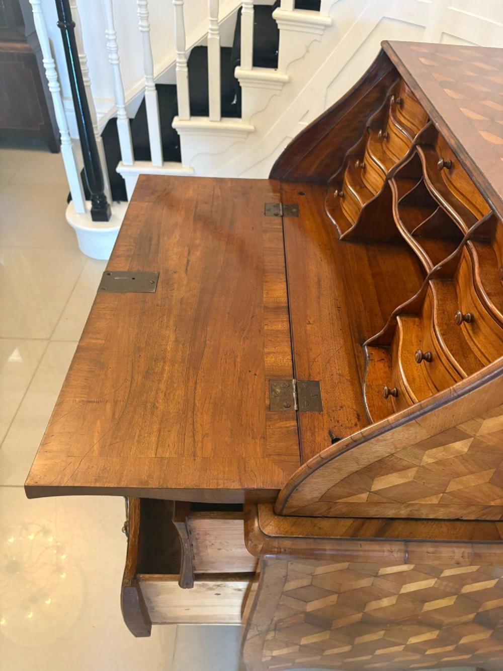 An 18th-century French walnut bureau featuring geometric parquetry inlay, a sloped fall front, a bombee body with two drawers, and brass mounts. View X