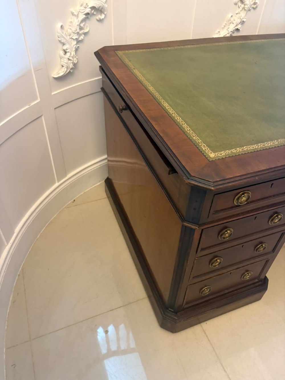 A Victorian mahogany pedestal desk featuring a green leather inset writing surface, nine drawers with brass ring pulls, and a plinth base. View III