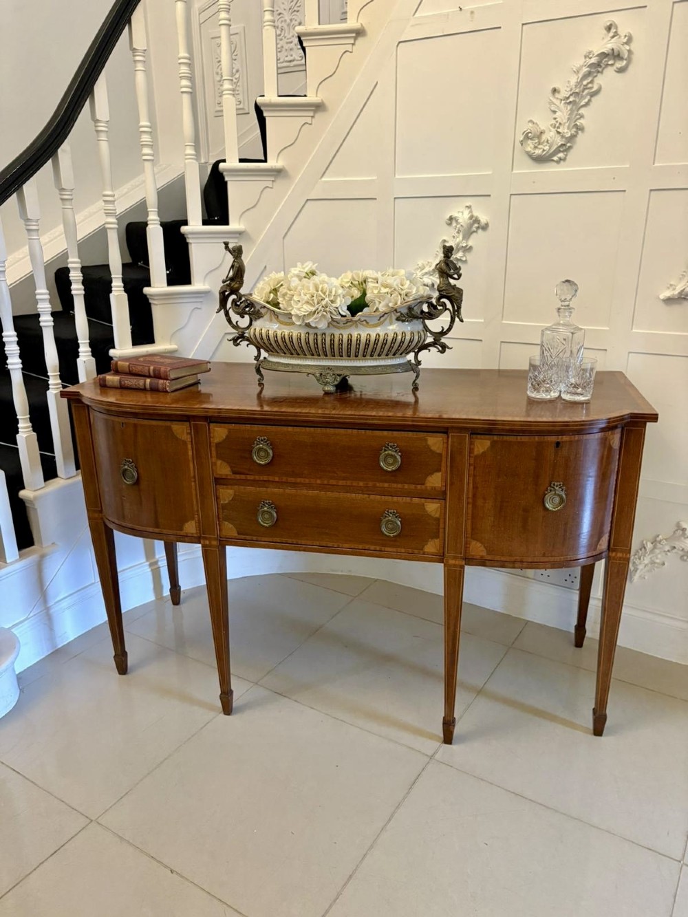 An Edwardian mahogany sideboard featuring satinwood crossbanded inlay, central drawers, flanking curved cupboards, brass ring handles, and square tapered legs. View III