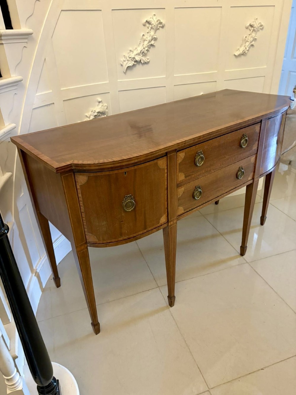 An Edwardian mahogany sideboard featuring satinwood crossbanded inlay, central drawers, flanking curved cupboards, brass ring handles, and square tapered legs. View VII