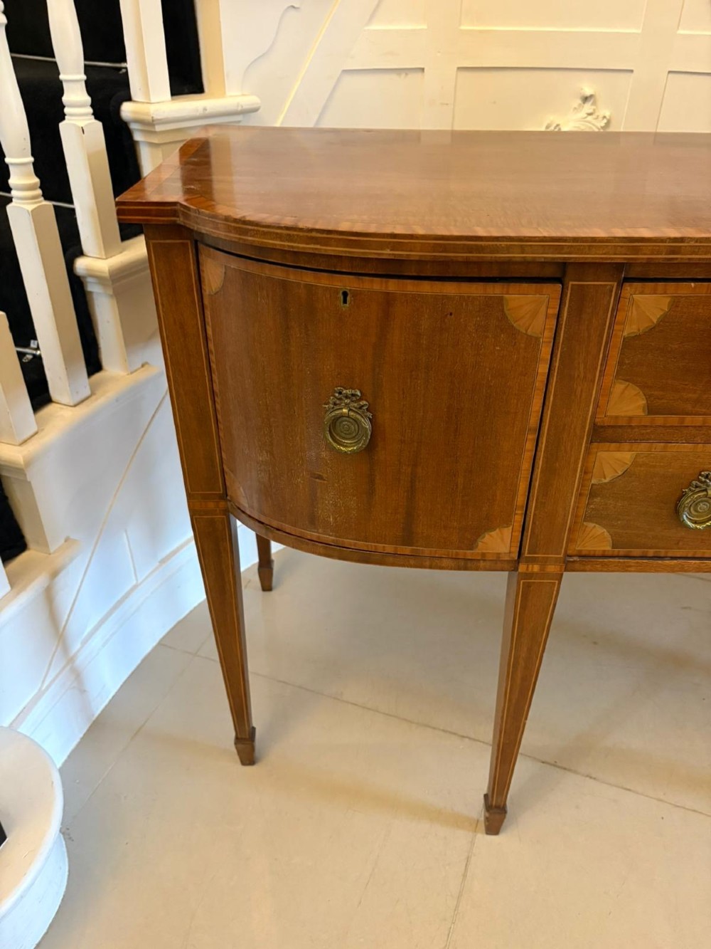 An Edwardian mahogany sideboard featuring satinwood crossbanded inlay, central drawers, flanking curved cupboards, brass ring handles, and square tapered legs. View VIII