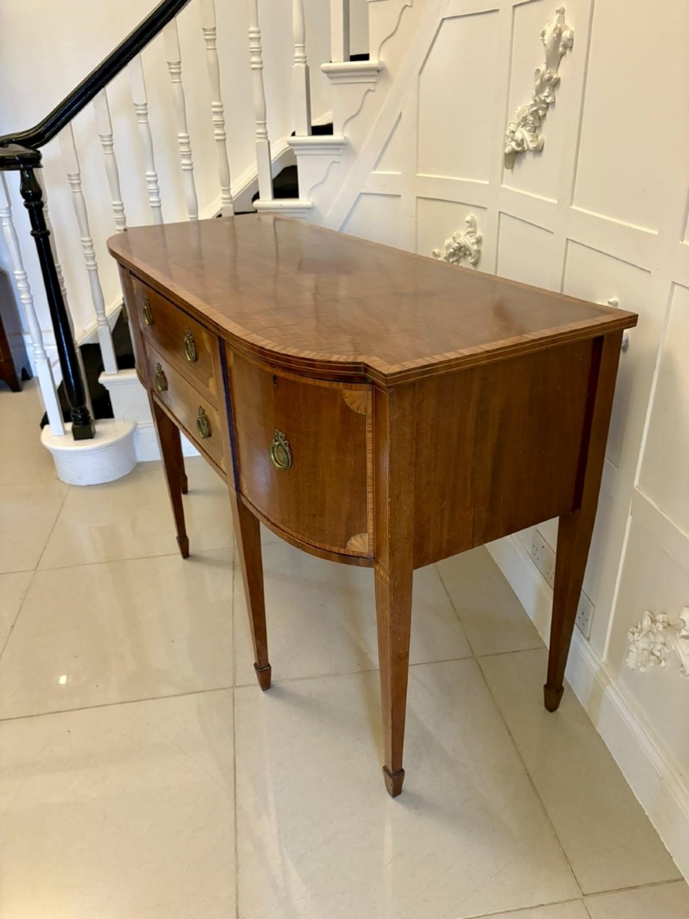 An Edwardian mahogany sideboard featuring satinwood crossbanded inlay, central drawers, flanking curved cupboards, brass ring handles, and square tapered legs. View XI