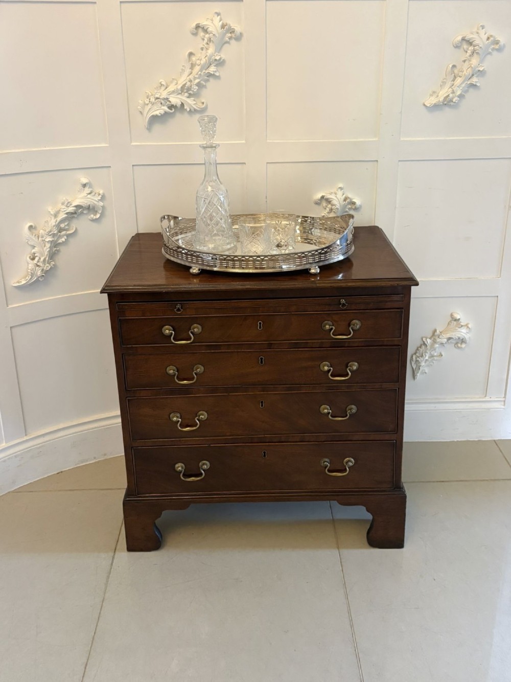 A small Georgian mahogany chest of drawers featuring four graduated drawers with brass swan-neck handles, a pull-out brushing slide, and bracket feet. View VII