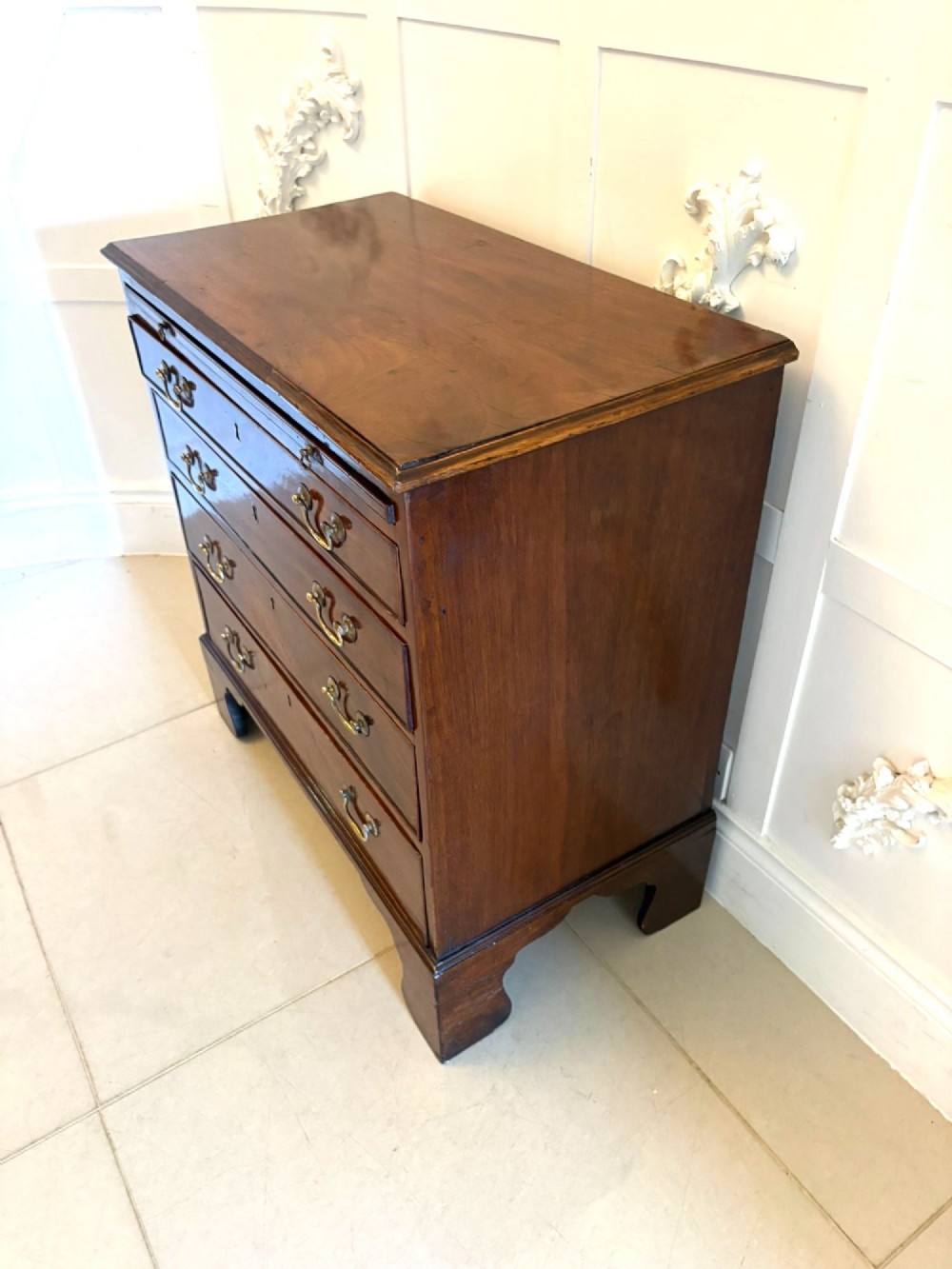 A small Georgian mahogany chest of drawers featuring four graduated drawers with brass swan-neck handles, a pull-out brushing slide, and bracket feet. View VIII