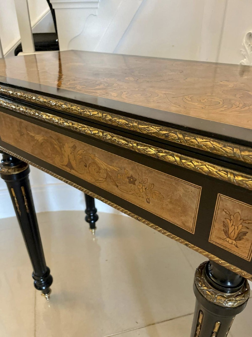 An antique French ebonised and walnut marquetry fold-over card table with gilt bronze mounts and fluted legs. View X