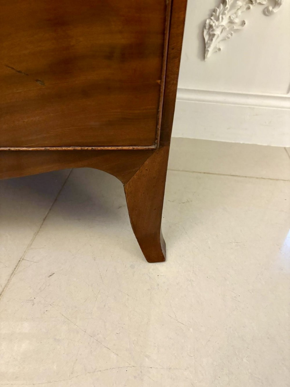 A George III mahogany bow-fronted chest featuring two short over three long graduating drawers with brass oval handles and splayed bracket feet. View III