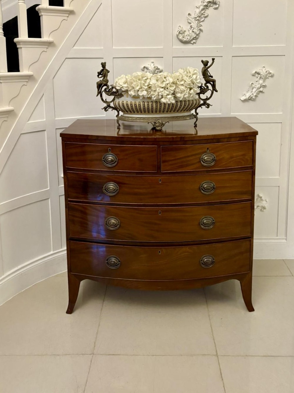 A George III mahogany bow-fronted chest featuring two short over three long graduating drawers with brass oval handles and splayed bracket feet. View IV