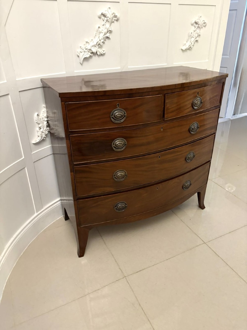 A George III mahogany bow-fronted chest featuring two short over three long graduating drawers with brass oval handles and splayed bracket feet. View V