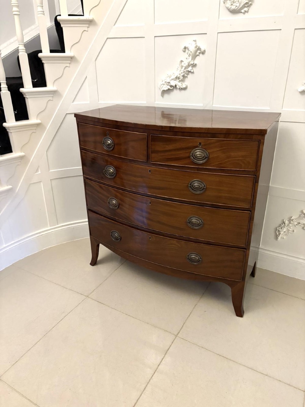 A George III mahogany bow-fronted chest featuring two short over three long graduating drawers with brass oval handles and splayed bracket feet. View VII