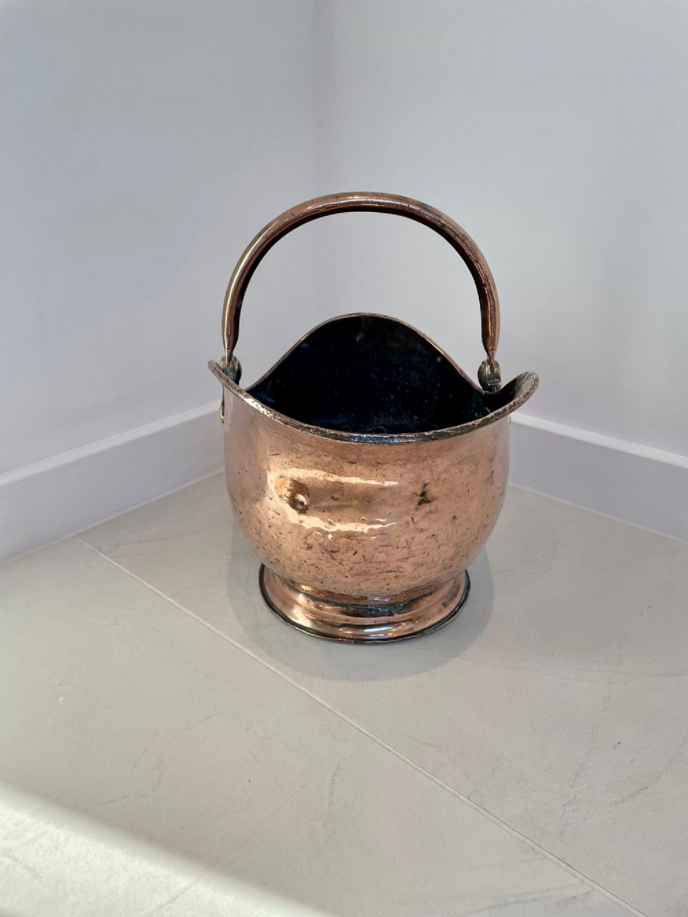 An antique George III copper helmet-shaped coal scuttle featuring an overhead swing handle, a rear loop handle, and a circular stepped pedestal base. View IV