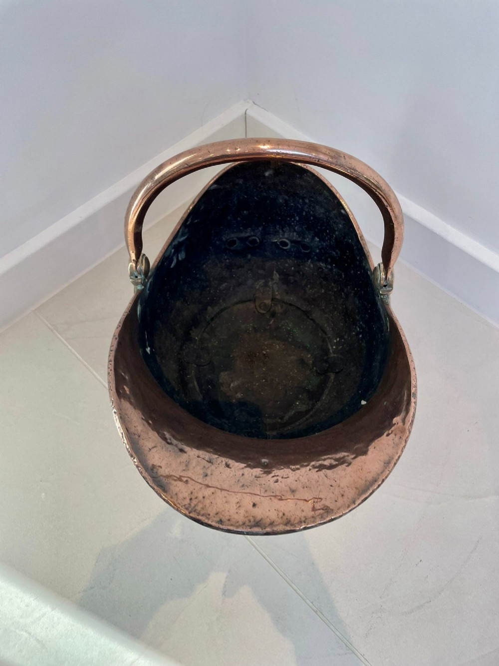 An antique George III copper helmet-shaped coal scuttle featuring an overhead swing handle, a rear loop handle, and a circular stepped pedestal base. View V