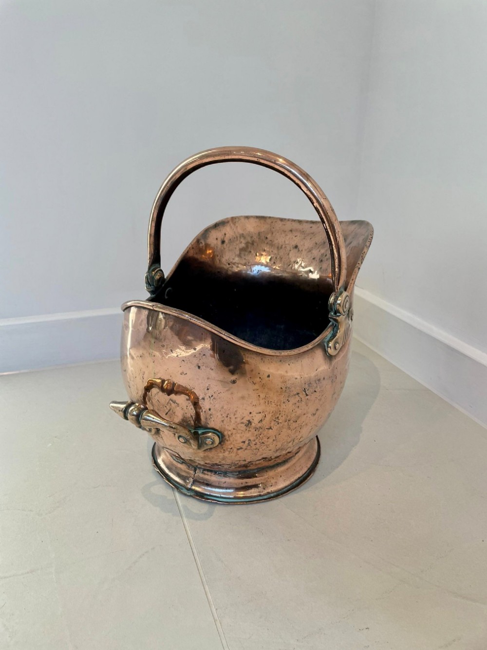 An antique George III copper helmet-shaped coal scuttle featuring an overhead swing handle, a rear loop handle, and a circular stepped pedestal base. View IX