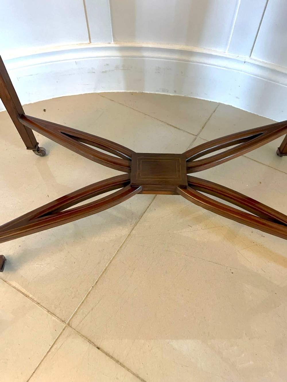 An Edwardian dark rosewood folding card table with floral satinwood corner inlays and an X-frame stretcher resting on brass castors. View IV