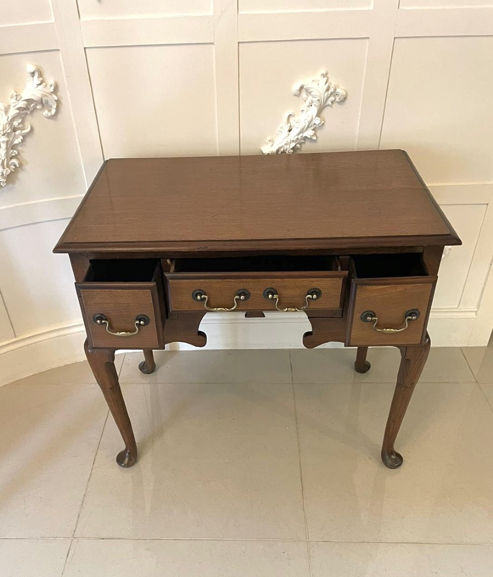 An 18th-century George III oak lowboy featuring three drawers with brass swan-neck handles, a shaped apron, and cabriole legs ending in pad feet. View VI
