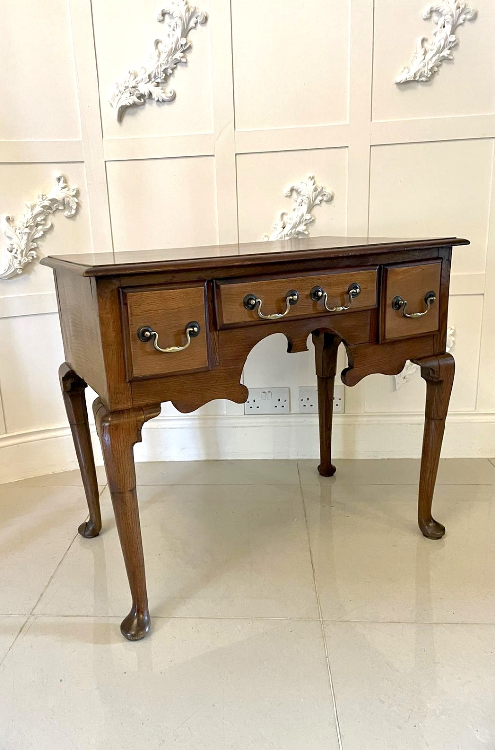 An 18th-century George III oak lowboy featuring three drawers with brass swan-neck handles, a shaped apron, and cabriole legs ending in pad feet. View XII