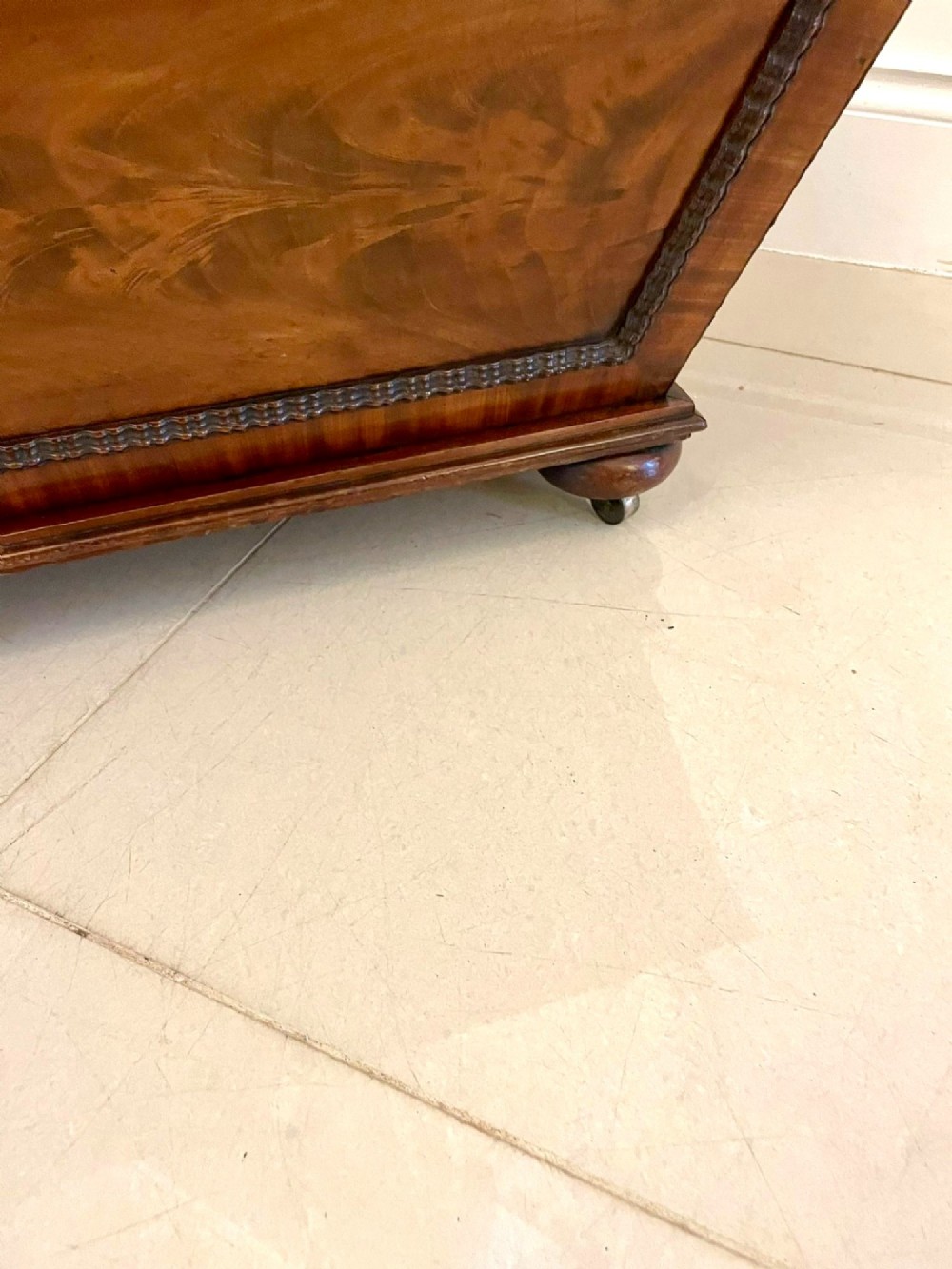 A William IV sarcophagus-shaped mahogany wine cooler featuring carved egg-and-dart moulding and a stepped lid set on short legs with castors. View V