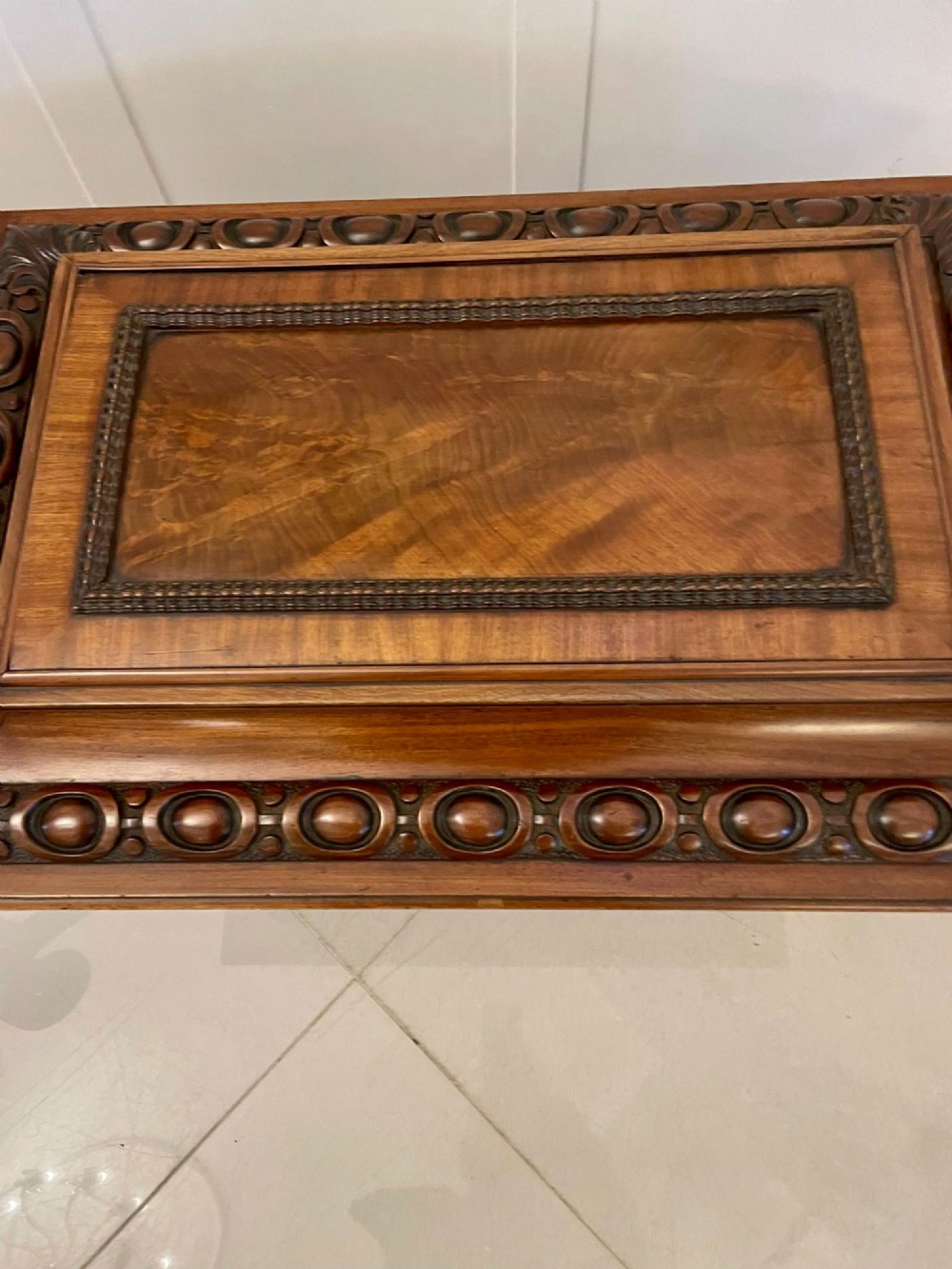 A William IV sarcophagus-shaped mahogany wine cooler featuring carved egg-and-dart moulding and a stepped lid set on short legs with castors. View VI