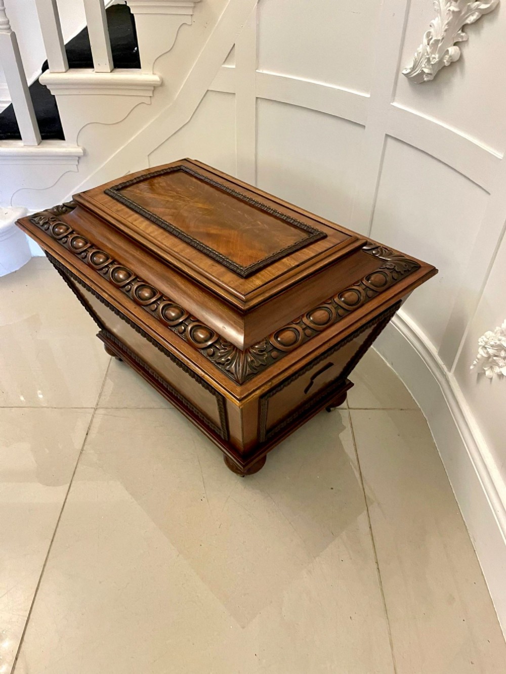 A William IV sarcophagus-shaped mahogany wine cooler featuring carved egg-and-dart moulding and a stepped lid set on short legs with castors. View IX
