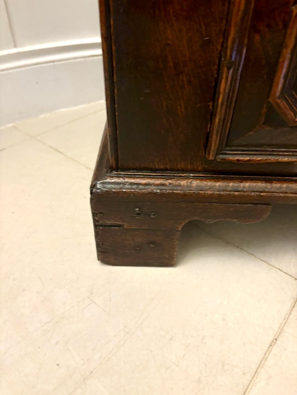 A dark oak Jacobean chest of drawers featuring geometric moulded drawer fronts and brass drop handles. View VII