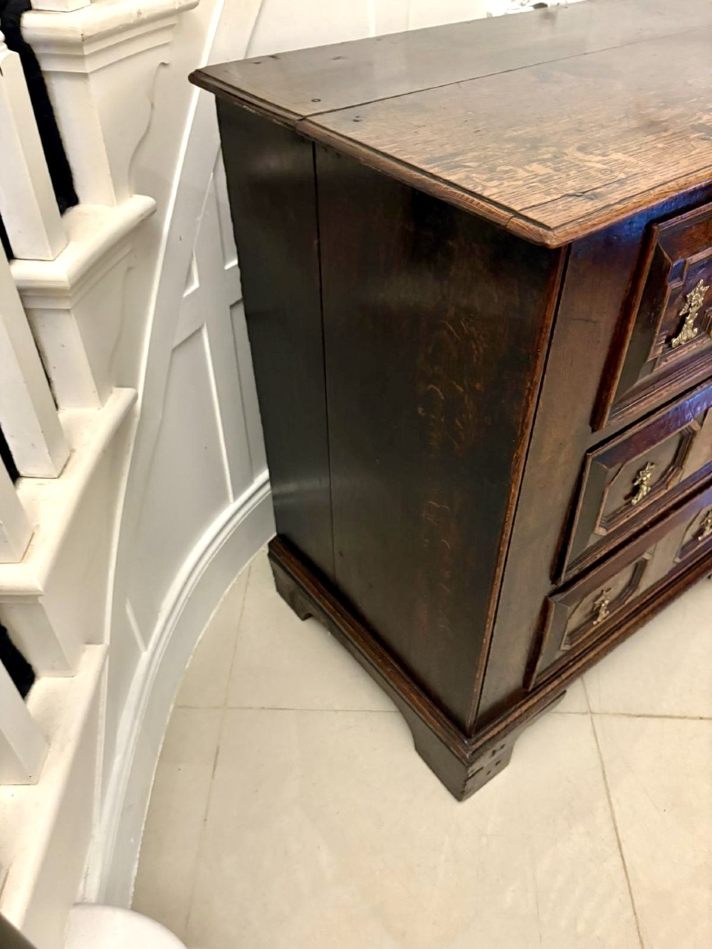 A dark oak Jacobean chest of drawers featuring geometric moulded drawer fronts and brass drop handles. View VIII