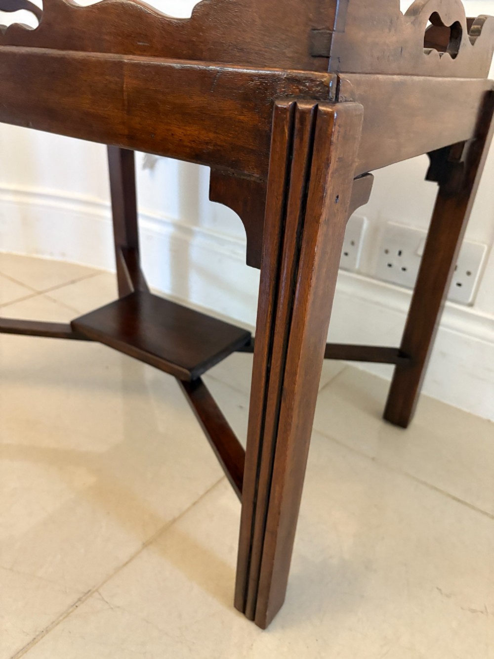 An Edwardian dark mahogany butlers tray featuring cut-out hand holes and a galleried rim, resting on a sturdy matching wooden stand with X-stretchers. View IV