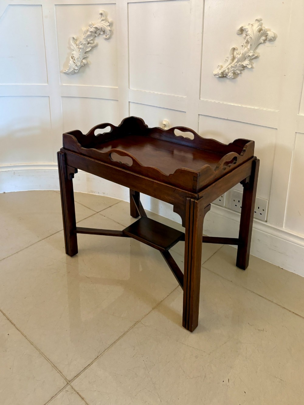 An Edwardian dark mahogany butlers tray featuring cut-out hand holes and a galleried rim, resting on a sturdy matching wooden stand with X-stretchers. View VII