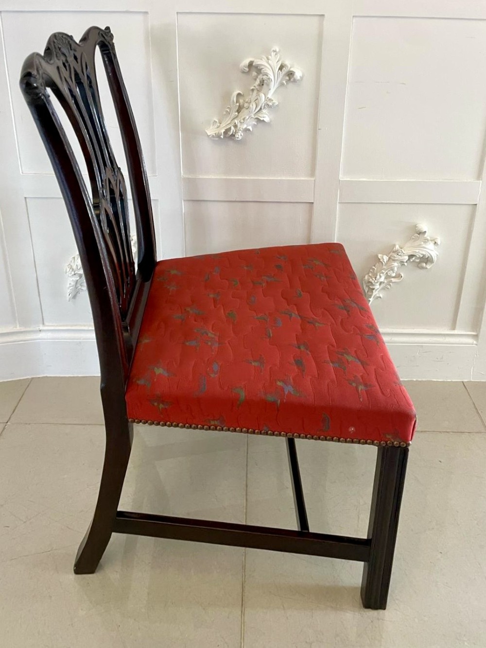 A set of twelve carved dark mahogany dining chairs featuring intricate pierced back splats and red patterned upholstered seats. View III