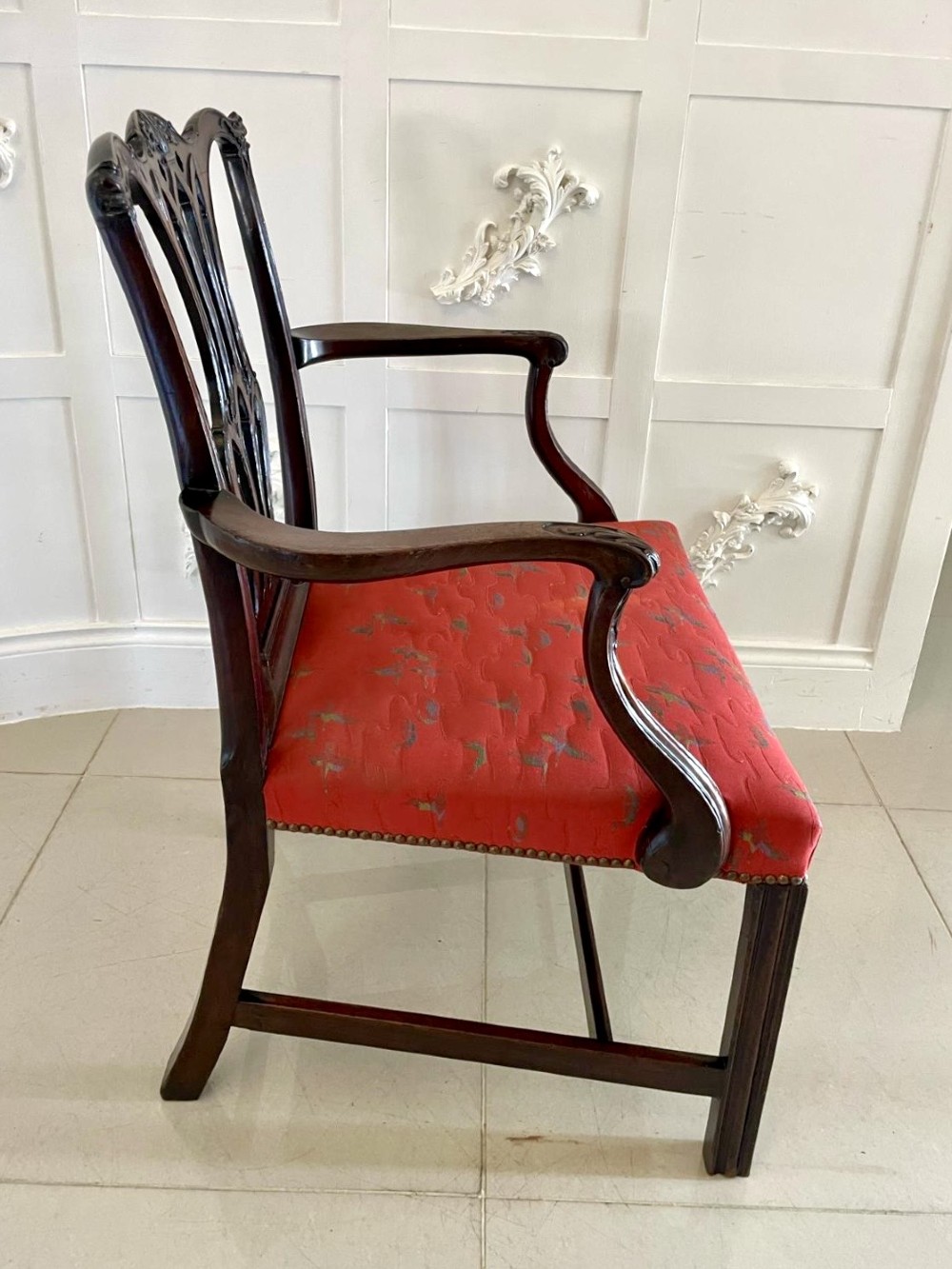 A set of twelve carved dark mahogany dining chairs featuring intricate pierced back splats and red patterned upholstered seats. View VII