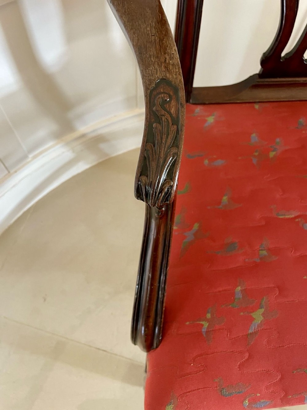 A set of twelve carved dark mahogany dining chairs featuring intricate pierced back splats and red patterned upholstered seats. View IX