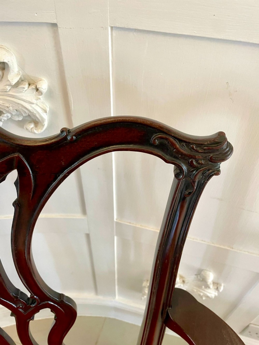 A set of twelve carved dark mahogany dining chairs featuring intricate pierced back splats and red patterned upholstered seats. View XI