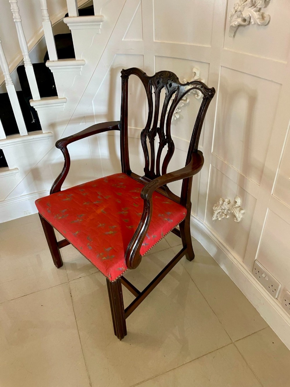 A set of twelve carved dark mahogany dining chairs featuring intricate pierced back splats and red patterned upholstered seats. View XII