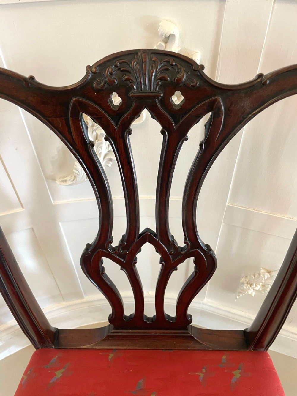 A set of twelve carved dark mahogany dining chairs featuring intricate pierced back splats and red patterned upholstered seats. View XIII