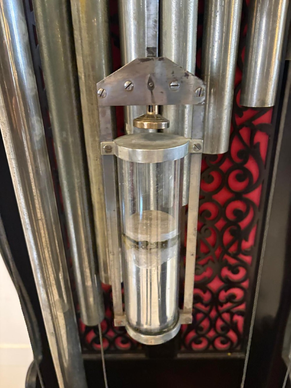 A tall carved dark mahogany longcase clock featuring an ornate pediment, brass dial with moon phase indicator, and a glazed door displaying nine tubular chimes. View IV