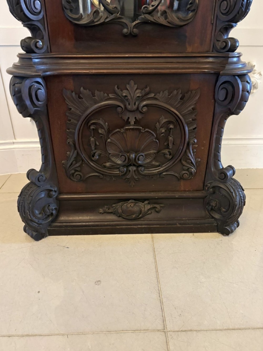 A tall carved dark mahogany longcase clock featuring an ornate pediment, brass dial with moon phase indicator, and a glazed door displaying nine tubular chimes. View X